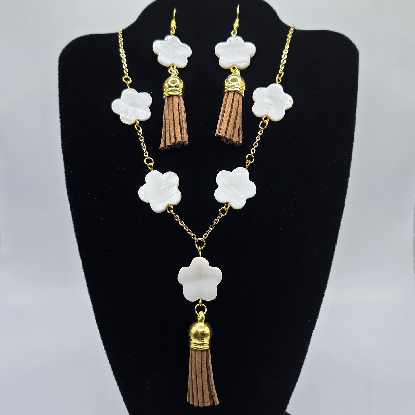 Jewelry set with necklace and earrings on a black stand against a gray background