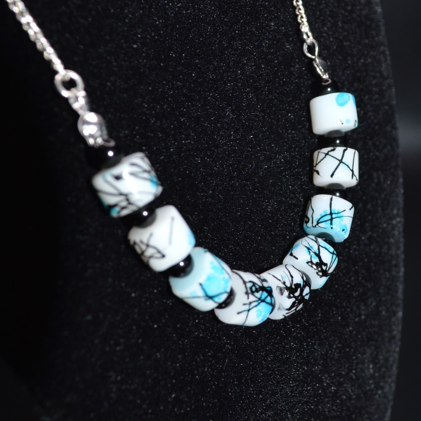 Necklace with white beads featuring black and blue patterns on a black background