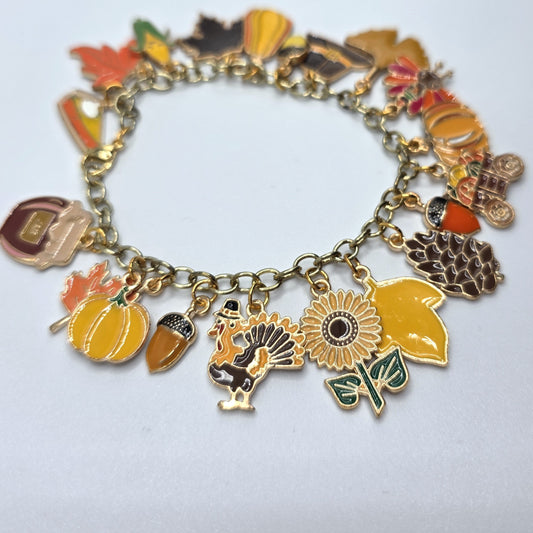 Bracelet with various charms including pumpkins, leaves, a sunflower, and a turkey on a white background