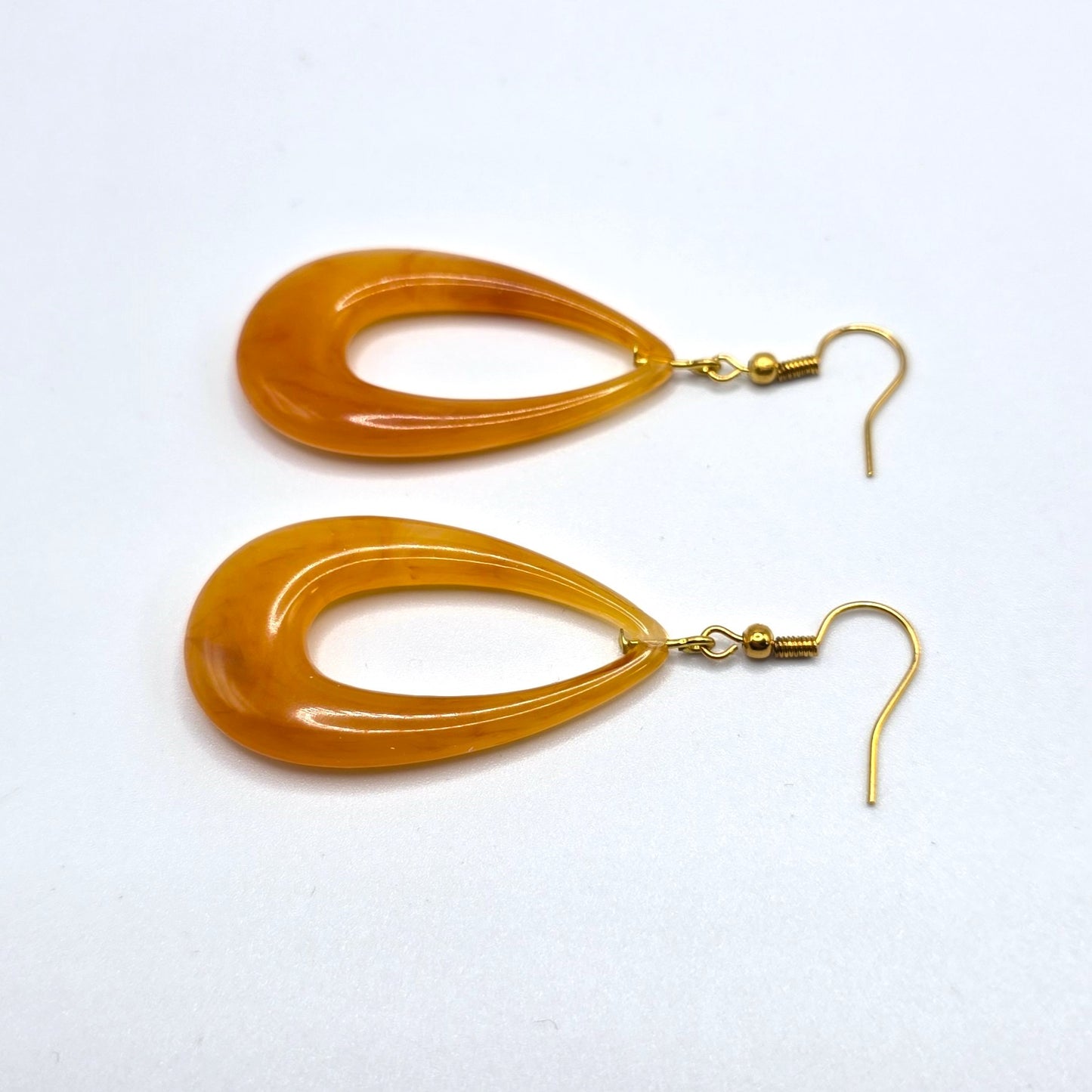 Pair of orange earrings with gold hooks on a white background