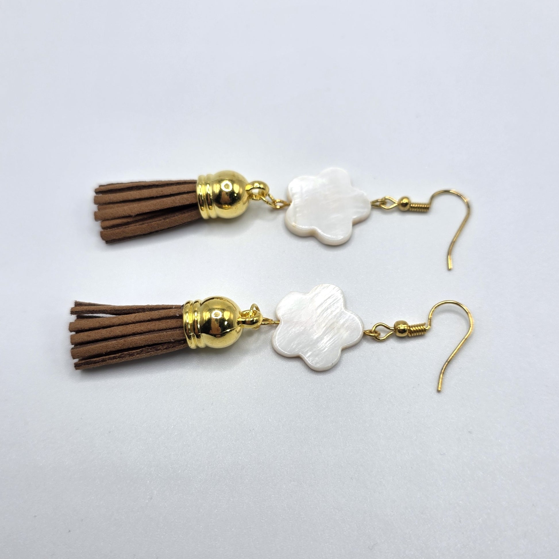 Pair of earrings with tassels and gold accents on a light gray background