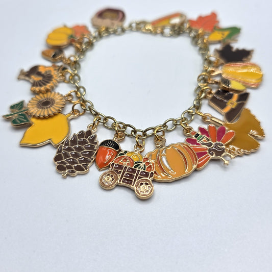 Charms on a bracelet with autumn-themed designs on a white background