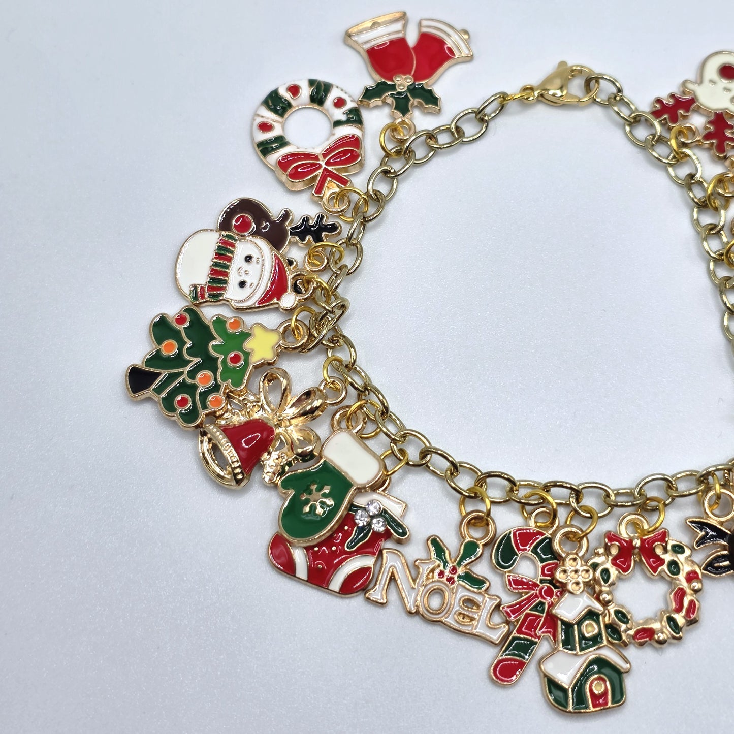 Gold bracelet with Christmas-themed charms on a light gray background