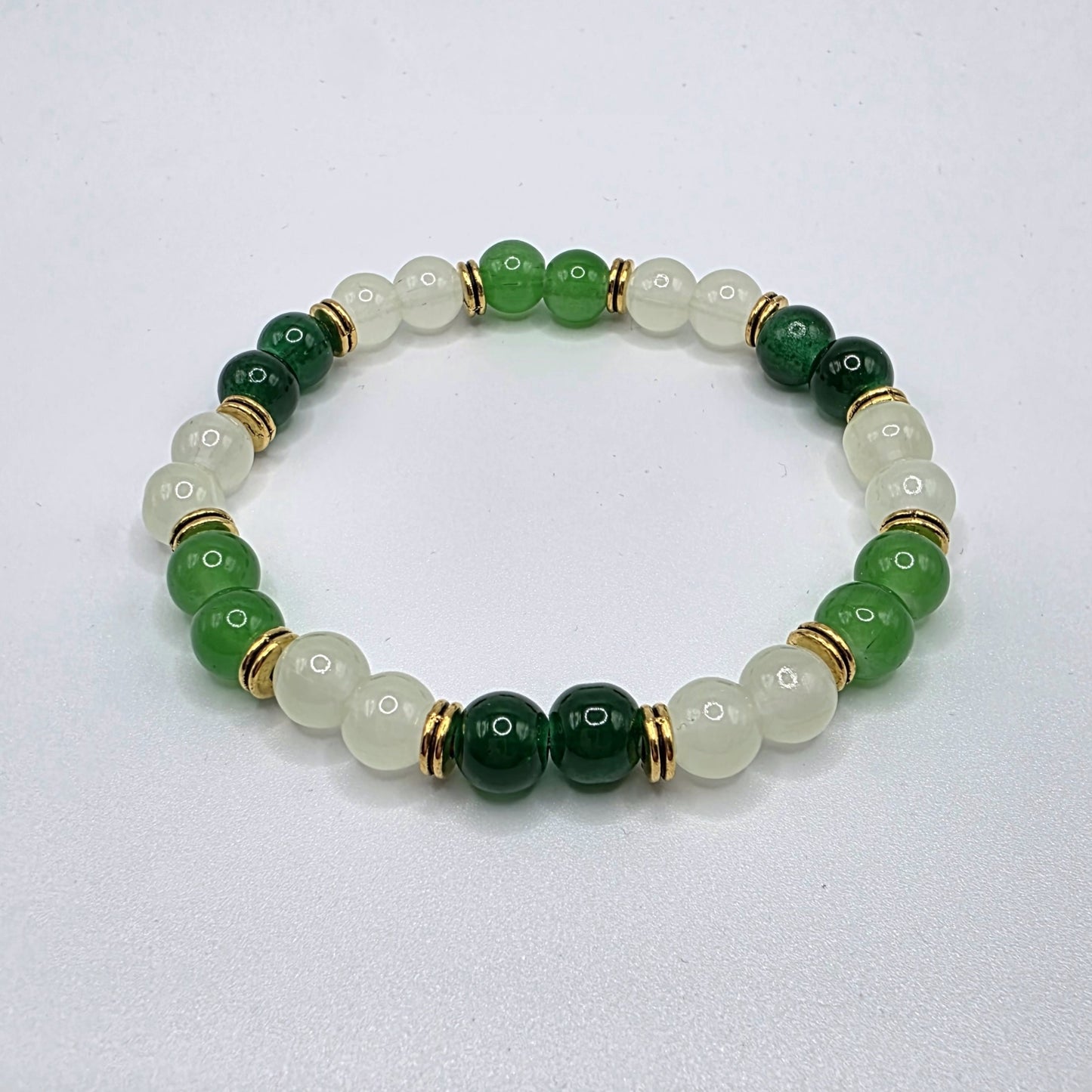 Beaded bracelet with green and gold beads on a light gray background