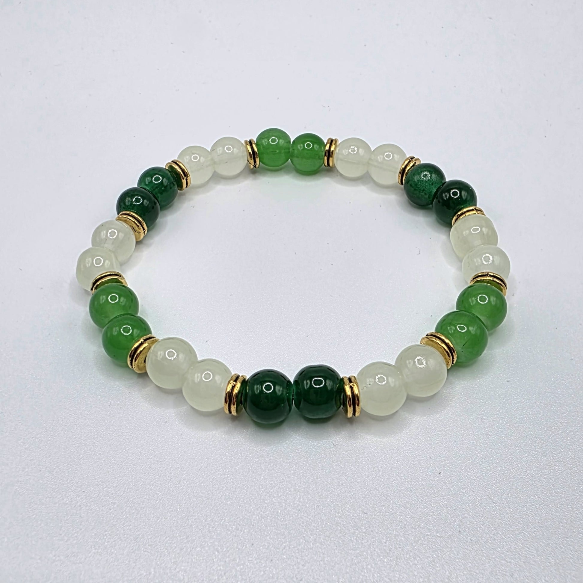 Beaded bracelet with green and gold beads on a light gray background