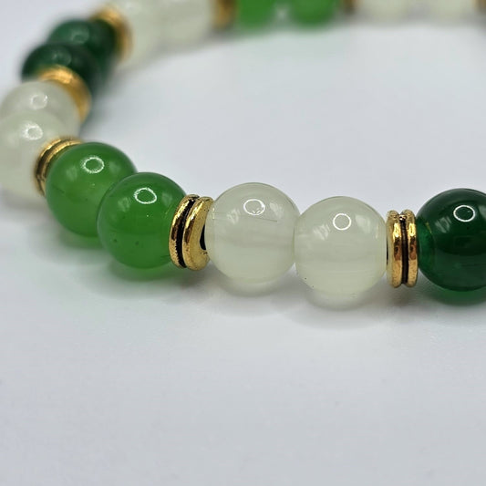 Close-up of a bracelet with green and gold beads on a white background