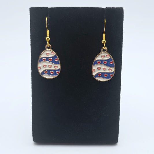 Easter egg-shaped earrings with heart patterns on a black stand against a white background