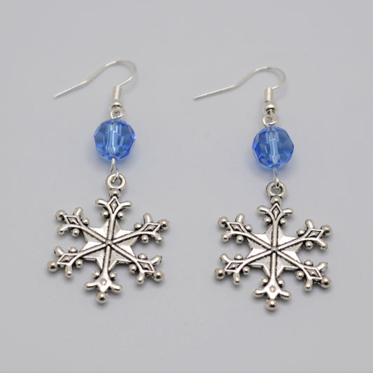 Silver snowflake earrings with blue beads on a gray background