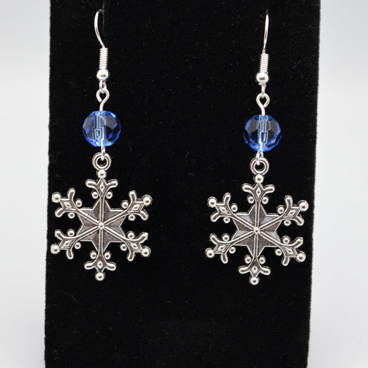 Silver snowflake earrings with blue beads on a black background