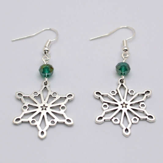 Silver snowflake earrings with green beads on a gray background