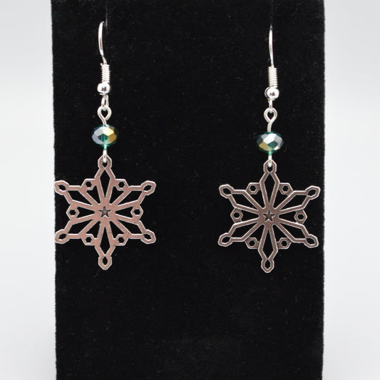 Silver snowflake earrings with green beads on a black background